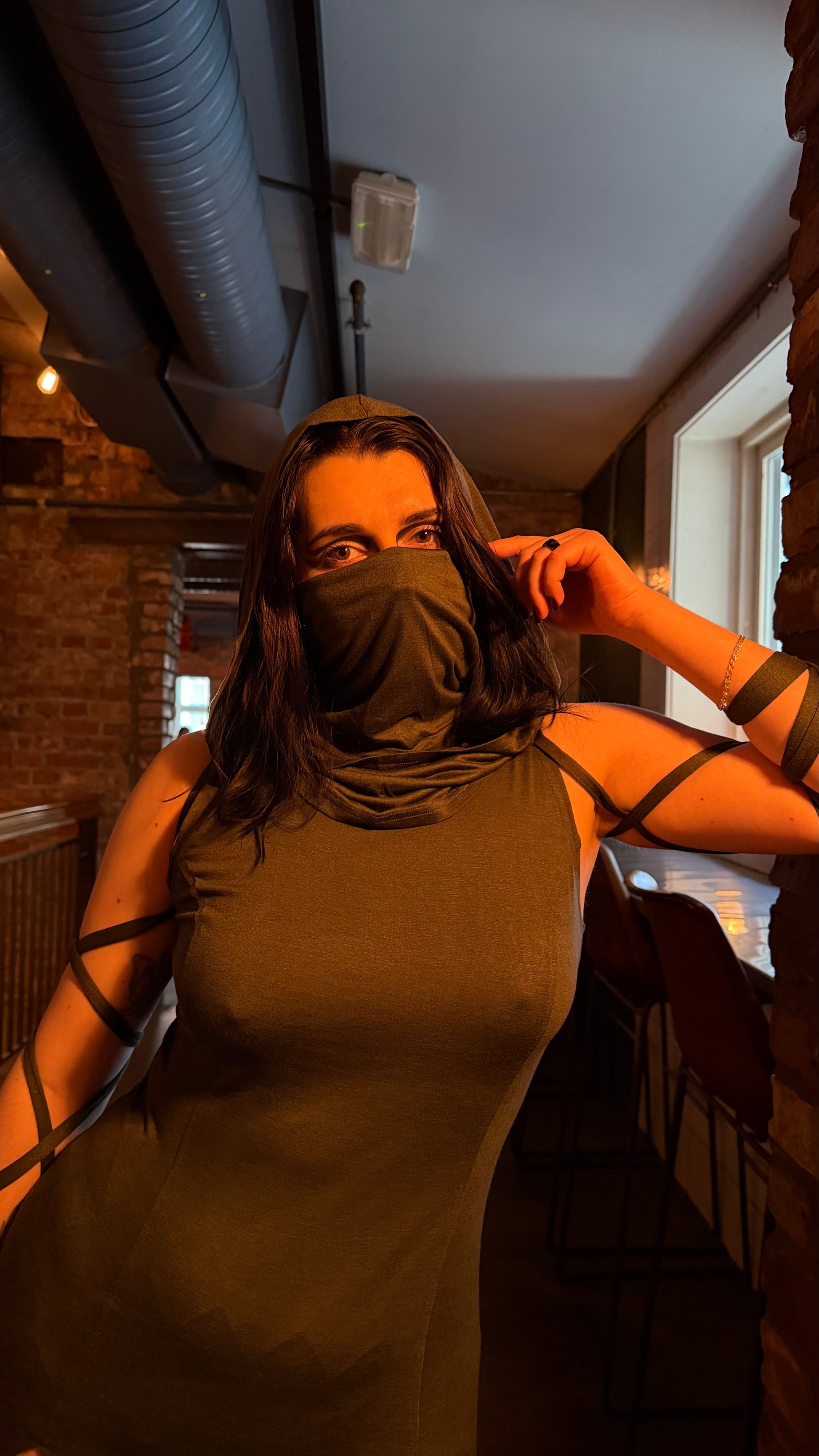 Woman wearing a green dress with a face covering in an indoor setting.