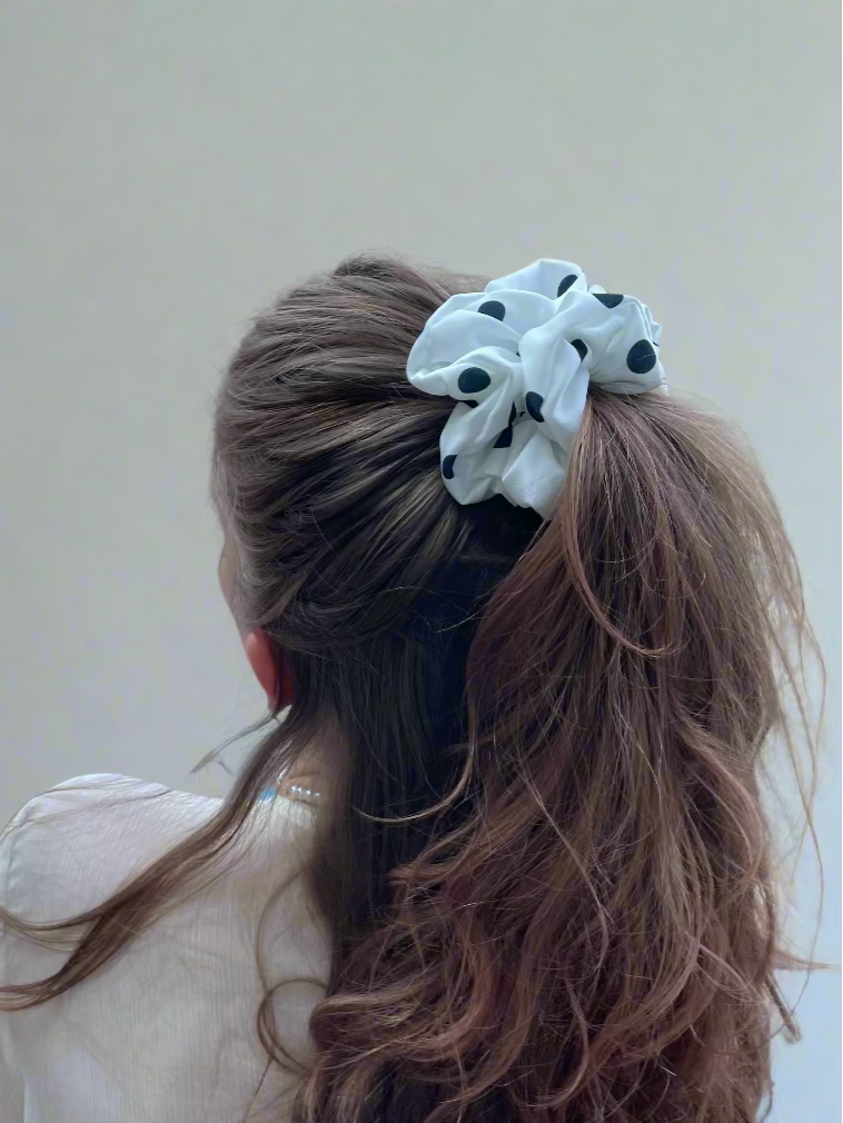 Person with wavy hair tied with a white scrunchie on a beach setting