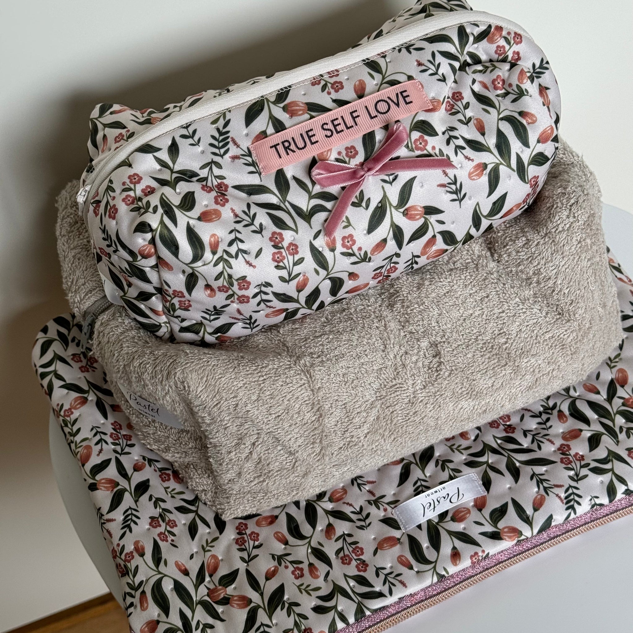 Floral-patterned pouches with 'True Self Love' text on a white surface