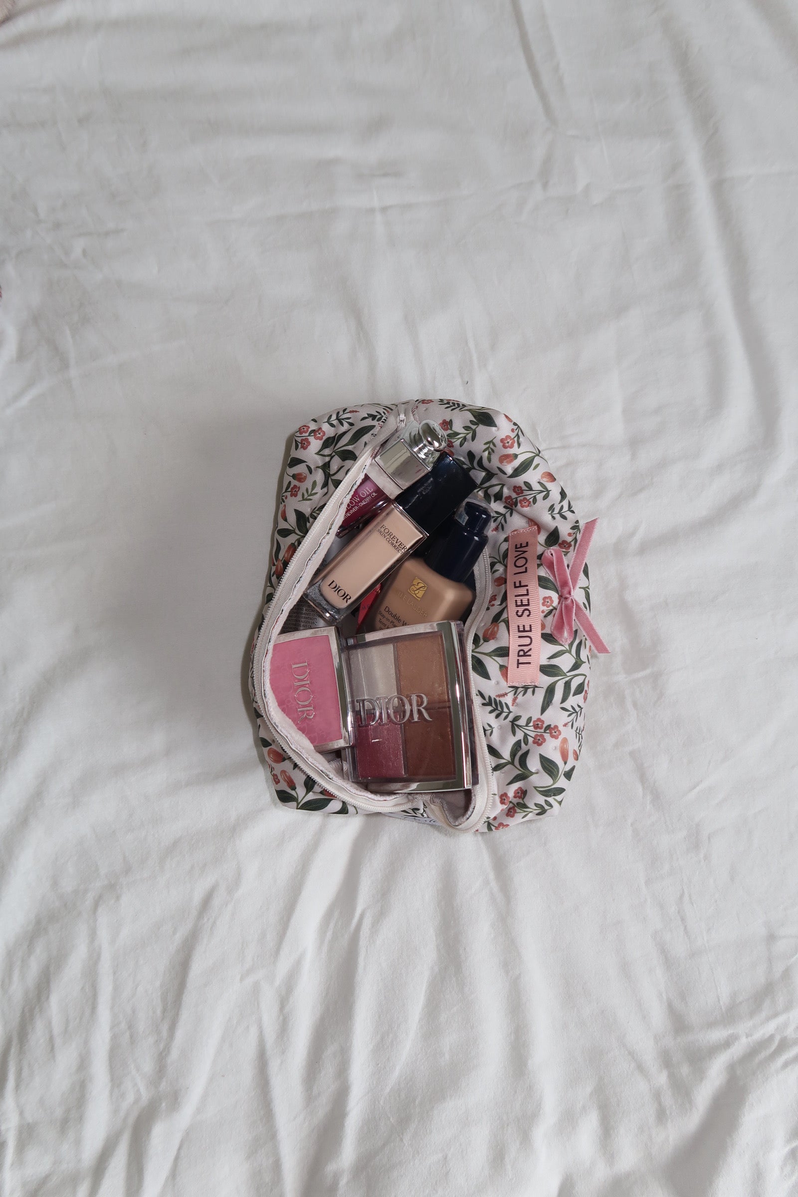 Makeup bag with cosmetics on a white bedspread