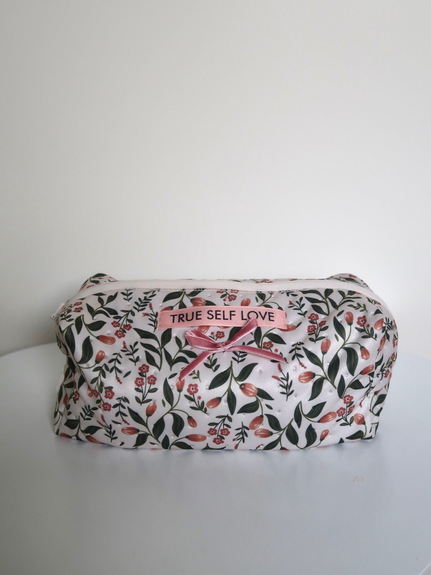 Floral-patterned pouch with 'True Self Love' text on a white background